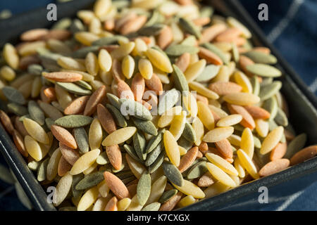 Dry Organic Tricolor Orzo Pasta in a Bowl Stock Photo