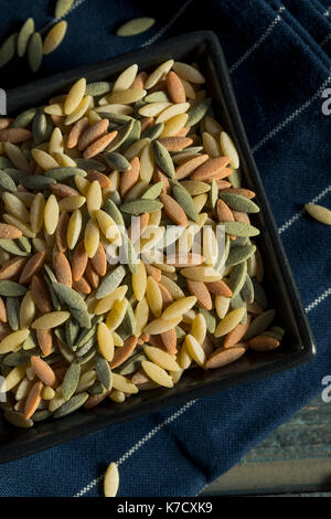 Dry Organic Tricolor Orzo Pasta in a Bowl Stock Photo