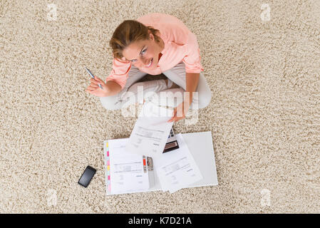 High Angle View Of Young Woman Doing Calculation At Home Stock Photo