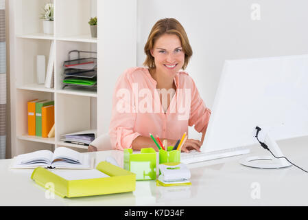 Young Happy Woman Working On Desktop Computer At Desk Stock Photo