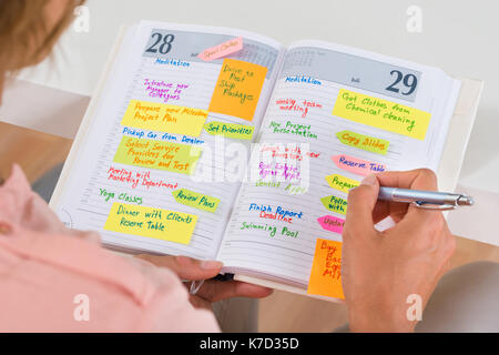 Close-up Of Woman Writing Important Note In Diary With Pen Stock Photo