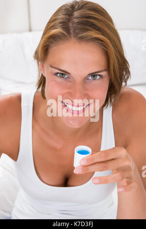 Portrait Of Young Happy Woman Holding Bottle Cap With Mouthwash Stock Photo