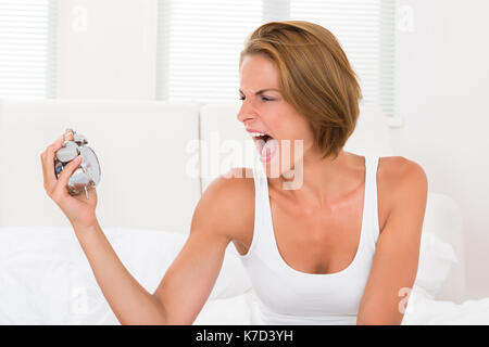Portrait Of Young Woman Screaming To The Alarm Clock Stock Photo