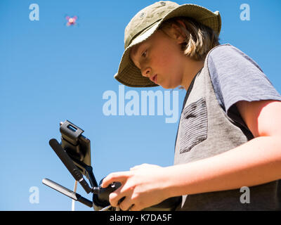 Low angle view of boy flying quadcopter using remote control against clear sky Stock Photo