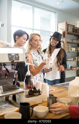 Happy female friends reading menu while standing at counter in cafeteria Stock Photo
