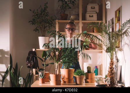 Woman watering potted plants using spray bottle at home Stock Photo