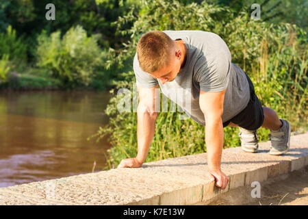 Man performing push ups by the river Stock Photo