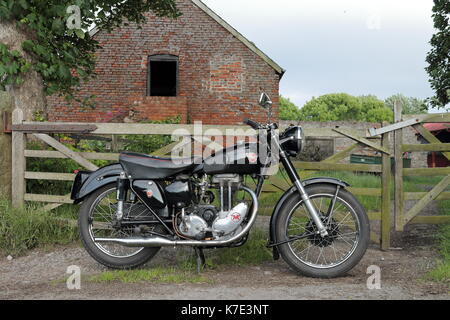 Restored historic Matchless G3LS 350cc classic motorcycle or motorbike parked near a farm gate in North Wales with a barn in the background. Stock Photo