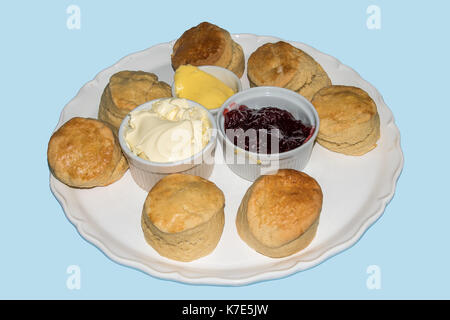 Scones with butter, jam and Cream on a large plate isolated on a blue background Stock Photo