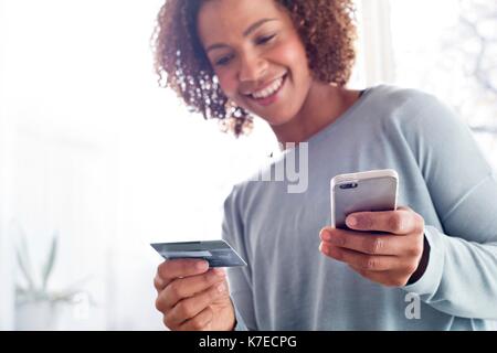 Mid adult woman holding credit card and cell phone. Stock Photo