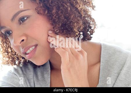 Portrait of mid adult woman touching face. Stock Photo