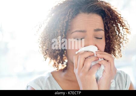 Mid adult woman blowing nose on tissue. Stock Photo