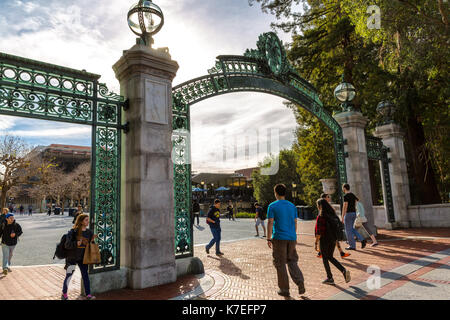 University of California at Berkeley main entrance into the campus. Students shown walking under the ornate landmark, Sather Gate, an iconic symbol. Stock Photo
