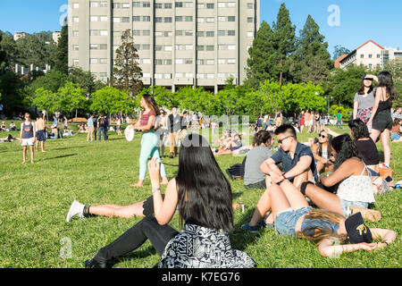 Students at the University of California Berkeley campus enjoying a warm spring day outdoors on the grass. Stock Photo