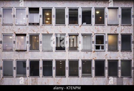 Office building in a downtown district, marble fronts and venetian blinds on windows, some offices illuminated Stock Photo