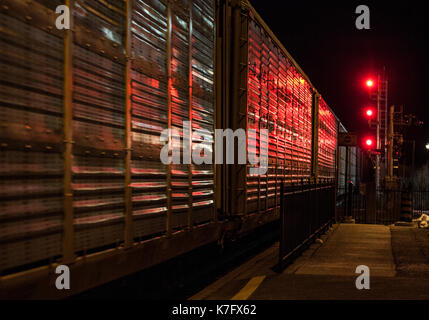 another train hauling empty car haulers late at night going through Brampton Stock Photo
