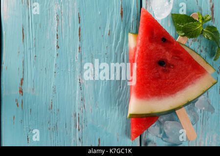 Pieces of ripe red watermelon and mint leaves on a wooden background with space for text. Top view Stock Photo