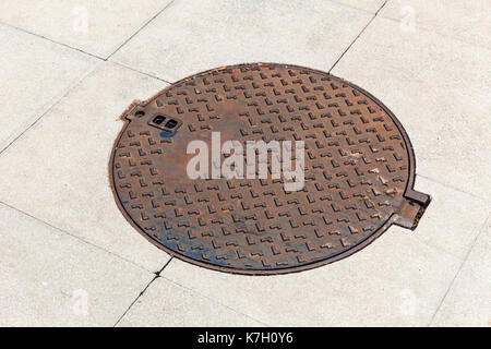 metal drain cap on the concrete of sewer cover on the walk way old strong steel iron and grungy rust. Stock Photo