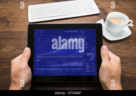 Close-up Of Person Hands With Digital Tablet Showing Graph At Desk Stock Photo