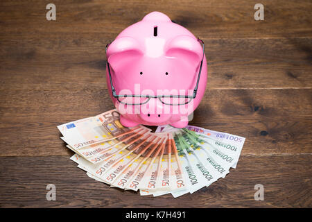 Close-up Of A Piggybank On Euro Banknotes With Eyeglasses Stock Photo