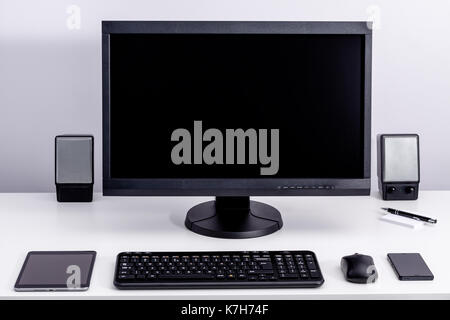 Blank black pc monitor on desktop in organized workplace. Stock Photo