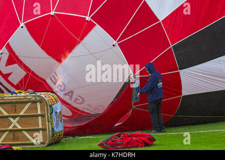 Longleat, Wiltshire UK. 15th September 2017. A mixed day of weather doesn't deter visitors enjoying the Sky Safari hot air balloons at Longleat. Inflating red hot air balloon showing basket and flames going inside. Credit: Carolyn Jenkins/Alamy Live News Stock Photo