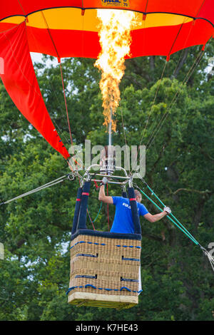 Longleat, Wiltshire UK. 15th September 2017. A mixed day of weather doesn't deter visitors enjoying the Sky Safari hot air balloons at Longleat. Man in hot air balloon basket tethered balloon in air with gas burners and flames. Credit: Carolyn Jenkins/Alamy Live News Stock Photo