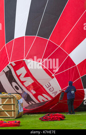 Longleat, Wiltshire UK. 15th September 2017. A mixed day of weather doesn't deter visitors enjoying the Sky Safari hot air balloons at Longleat. Inflating red hot air balloon showing basket and flames going inside. Credit: Carolyn Jenkins/Alamy Live News Stock Photo
