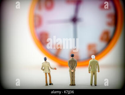 Miniature figures business men front insulated watch on white background, conceptual image Stock Photo