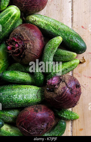 Freshly harvested pickling cucumbers and beetroots on light wooden board from above. Stock Photo