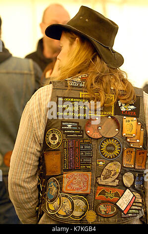 a motorcycle gang member or rocker at a motorcycle and music event wearing a hat and a waistcoat covered in badges. Long haired biker wearing badges. Stock Photo