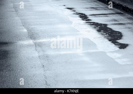 raindrops falling on puddles creating bubbles and circles. wet asphalt road. Stock Photo