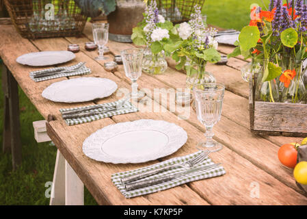 Wooden table setup for garden party or dinner reception. Stock Photo