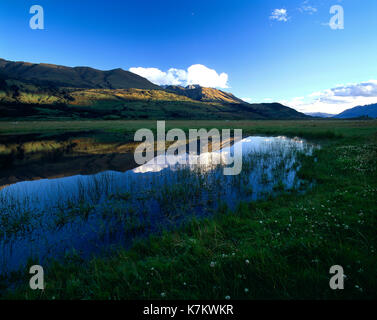 New Zealand. Queenstown Region. Hills reflected in valley lake in late evening shadows.