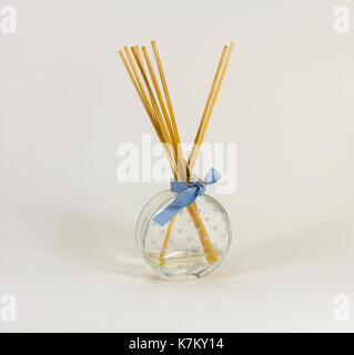 Reed fragrance diffuser, glass flask with heart motif markings and blue ribbon round the neck. Ratten reed sticks gradually diffuse scent. Stock Photo