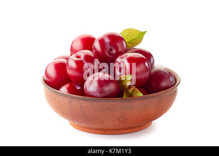 Ripe red plums in ceramic bowl on white Stock Photo