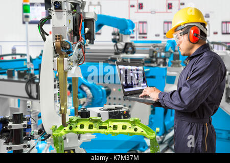 Engineer use computer checking industry robotic in factory Stock Photo