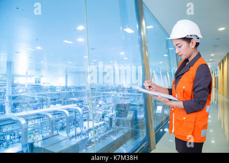 Business woman taking notes in production area of factory Stock Photo