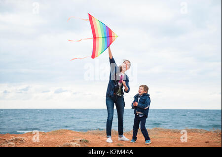 happy mother and child playing kite on sea coast in autumn Stock Photo
