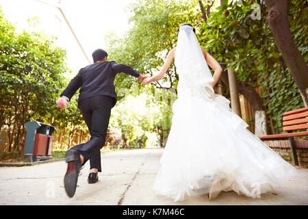 asian wedding couple running on street celebrating marriage. Stock Photo