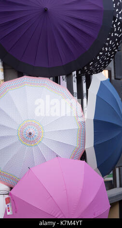 five pink, purple, black white and blue round umbrellas hanging in front of store.  Tightly composed shot.  Intricate patterns on edges of umbrellas Stock Photo