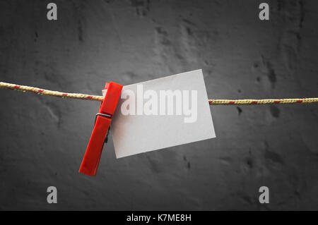 Paper note attach to rope with clothes pins on dark background Stock Photo