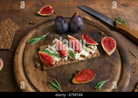 Small loaf of bread with cake cheese, figs and rosemary on the table Stock Photo