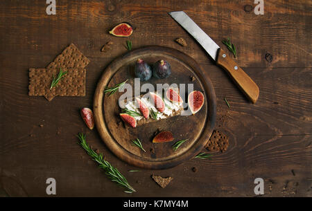 Small loaf of bread with cake cheese, figs and rosemary on the table Stock Photo