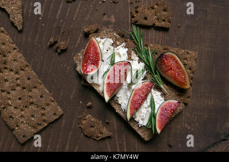 Small loaf of bread with cake cheese, figs and rosemary on the table Stock Photo
