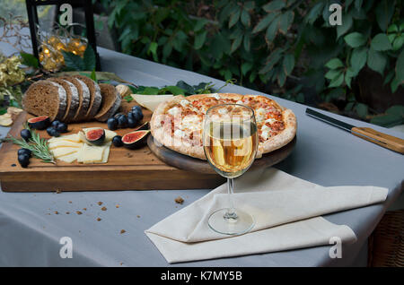 Pizza on board, cheese and leafs on the table Stock Photo