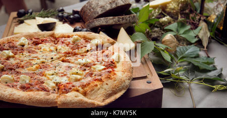 Pizza on board, cheese and leafs on the table Stock Photo