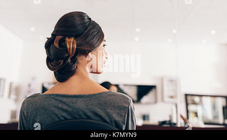 Woman sitting at the parlor in a fashionable hair style. Young woman displaying her trendy hairdo. Stock Photo