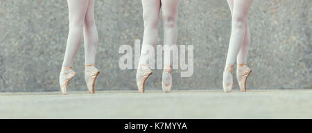 Closeup shot of legs of three female ballet dancers standing on their toes wearing pointe shoes. Ballet dancers practicing dance moves. Stock Photo