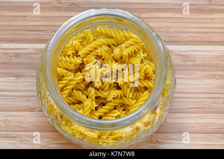 Fusilli pasta viewed from above in glass jar on wooden board Stock Photo